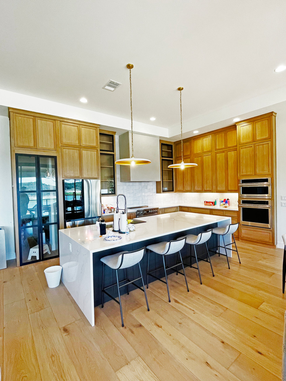 Inset custom cabinetry, black accent doors and kitchen island. White Oak Flooring, recessed lighting, and modern cement range hood.