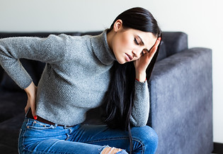 young-woman-suffering-back-ache-and-complaining-sitting-on-couch-in-the-living-room-at-hom
