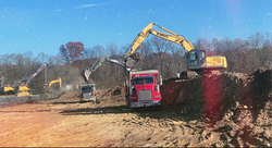 Excel Excavation excavator loading dirt into a dump truck at a job site in West Michigan.