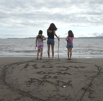 Still documental "130 hermanos" tres niñas de espalda en la playa mirando al mar