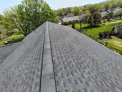 Aerial view of a gray asphalt shingle roof with surrounding landscape.