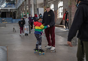 Instructor guiding a young skater through an indoor skate area