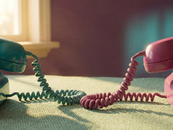 Vintage teal and magenta rotary telephones with intertwined cords on a sage surface, symbolising two-way communication in the double empathy problem.