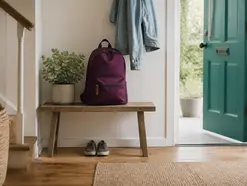 Packed school bag and jacket by a teal front door, daily routines used to build independence through prompting.