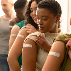 Group of people that just received vaccinations have their shirt sleeves rolled up and white bandages on their upper arms.
