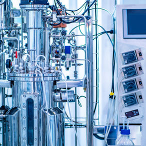 Industrial bioreactor with numerous tubes, gauges, sensors, wires and other inputs and outputs connected. 