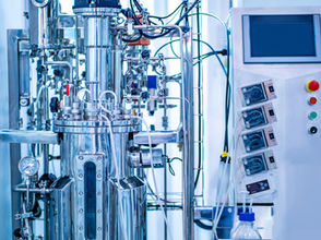 Industrial bioreactor with numerous tubes, gauges, sensors, wires and other inputs and outputs connected. 