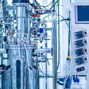 Industrial bioreactor with numerous tubes, gauges, sensors, wires and other inputs and outputs connected. 