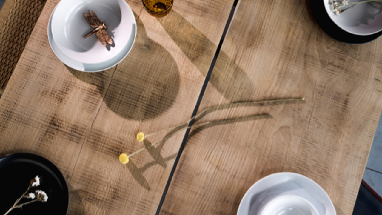 Close up of design craft oak table with plates, bowls, cups and elegant accessories. Cement floor. S