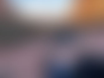 Man in a black Adidas cap smiles, standing on a rocky path in a canyon. Red cliffs and a vast vista are in the sunlit background.