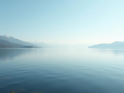 Looking over a hazy mountain lake, the lake takes up most of the picture with moutain peaks on each side of the top of the scene