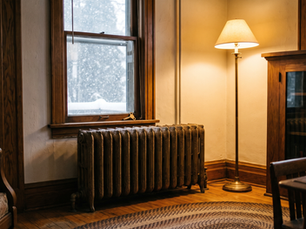 Cast iron radiator beneath a window in an older Chicago bungalow with snow falling outside