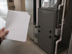 Homeowner reviewing utility rebate paperwork beside a newly installed furnace