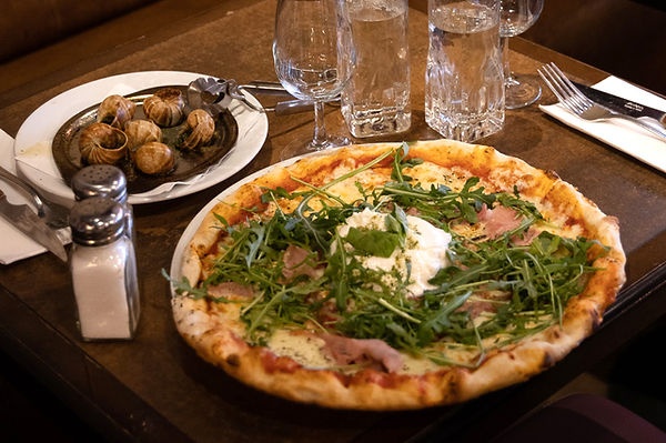 Image d'une pizza surmontée de jambon, roquette et burrata
