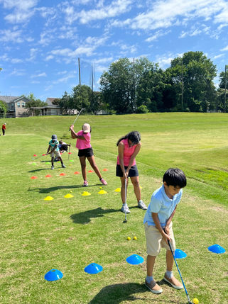 Rushi Oza guiding junior golfers on the driving range.