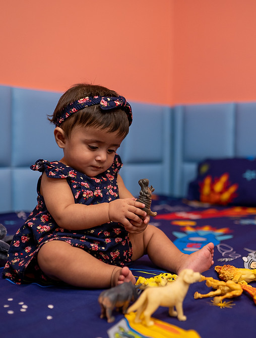 A girl sitting on a bed playing with animal toys at Daftarkhwan Vogue Day Care