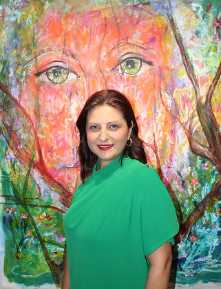 Artist Mira Mitrova from Art Mira Studio before vibrant painting of a face.
