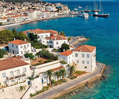 Mansions along the Spetses waterfront above turquoise sea, seen from above