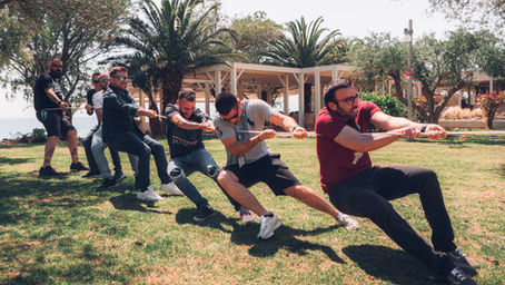 Team participating in a tug-of-war activity during an outdoor corporate offsite, demonstrating teamwork, collaboration, and friendly competition