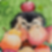 A whimsical watercolor illustration of a hedgehog peeking through a pile of colorful apples with a small apple balanced on its head, set against a green backdrop.