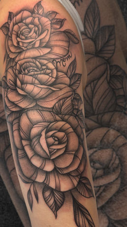 Black and grey rose tattoo with "Mom" text, wrapping over the shoulder and upper arm.