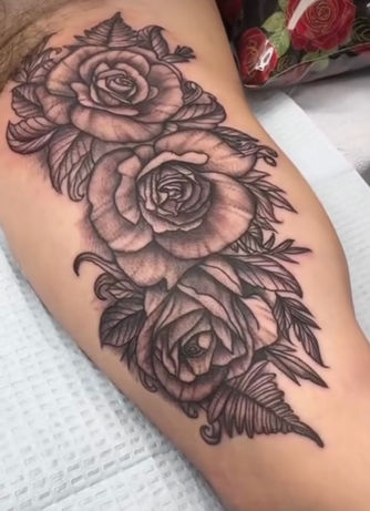 Inner arm tattoo of black and grey roses and leaves arranged in a cascading composition.