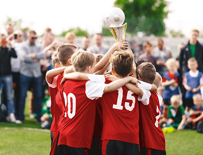 Happy children winning sports tournament. Kids in sports teams win trophies on tournaments