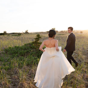 A bride and groom walking at sunset in an open field