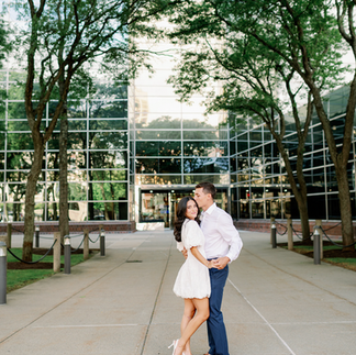Bride and groom smiling in front of large building