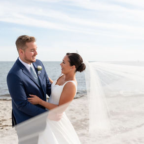 Bride and groom smiling at each other on the beach
