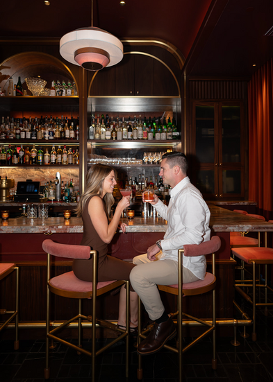 Man and woman toasting while sitting at bar
