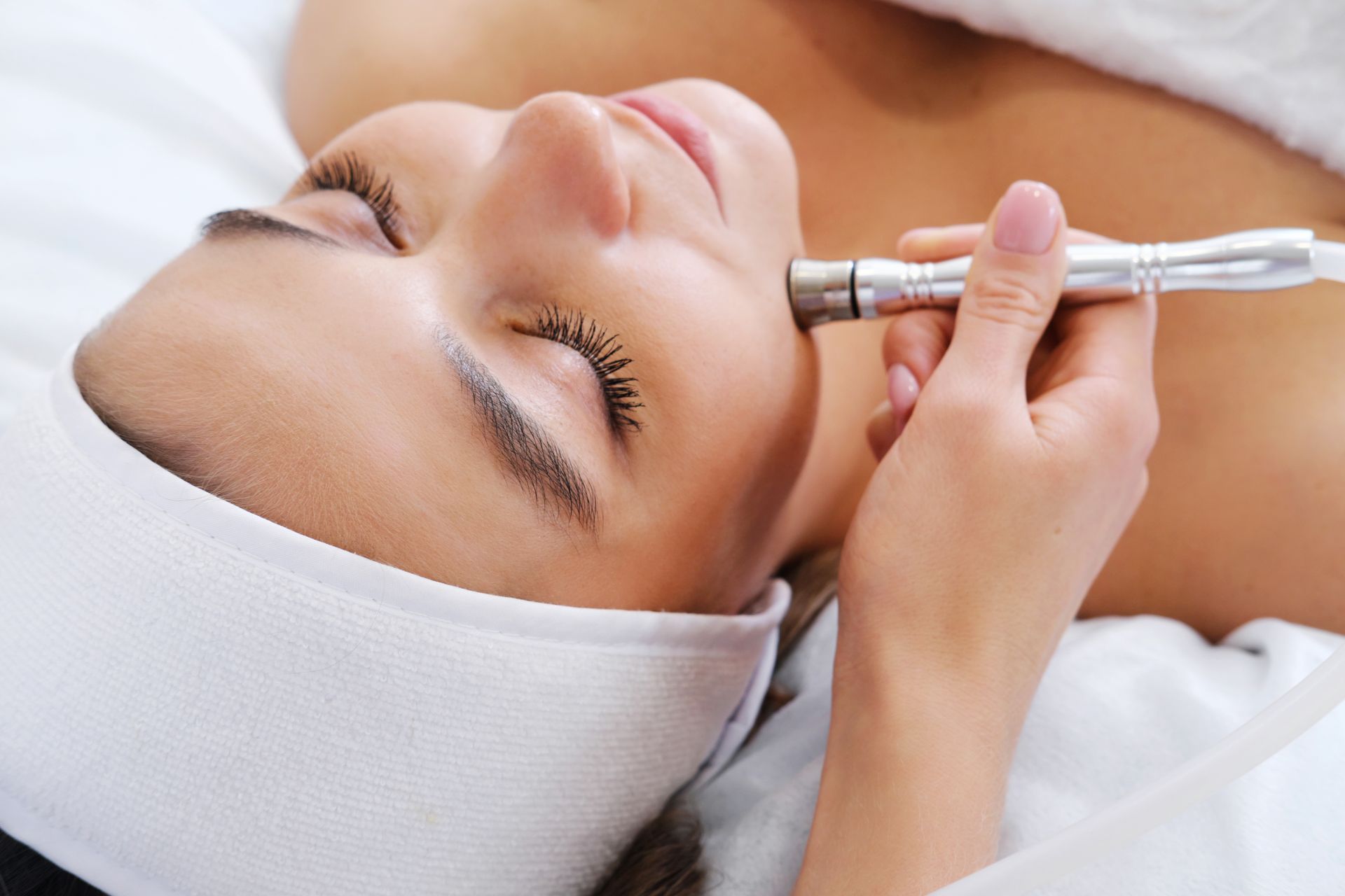 Close-up of diamond microdermabrasion facial treatment, bright clinical lighting, clean white setting