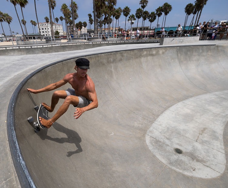 A surfskate instructor carving the bowl at the venice beach skatepark