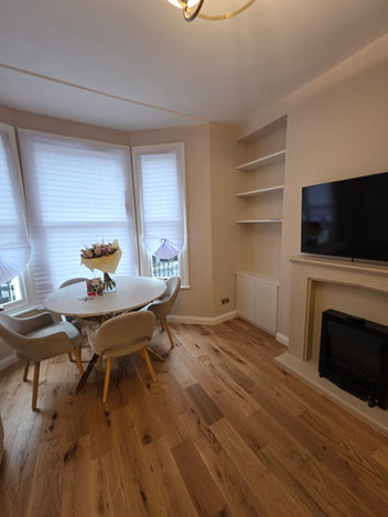 Bright modern living room, round dining table, fireplace, hardwood floor.