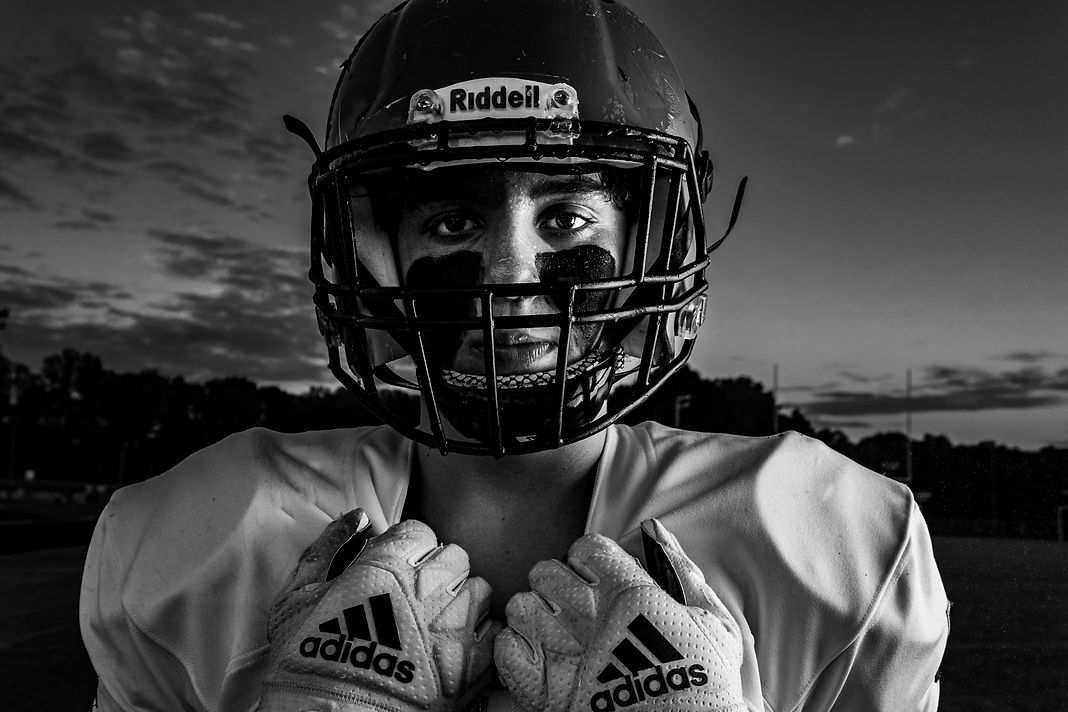 Gritty black and white football player portrait with a big sky in the background