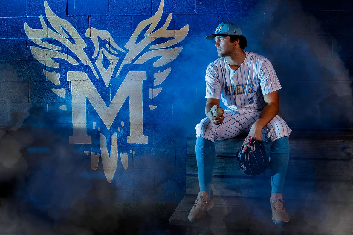 Baseball player waiting in the dugout with his glove next to the team logo with fog around him