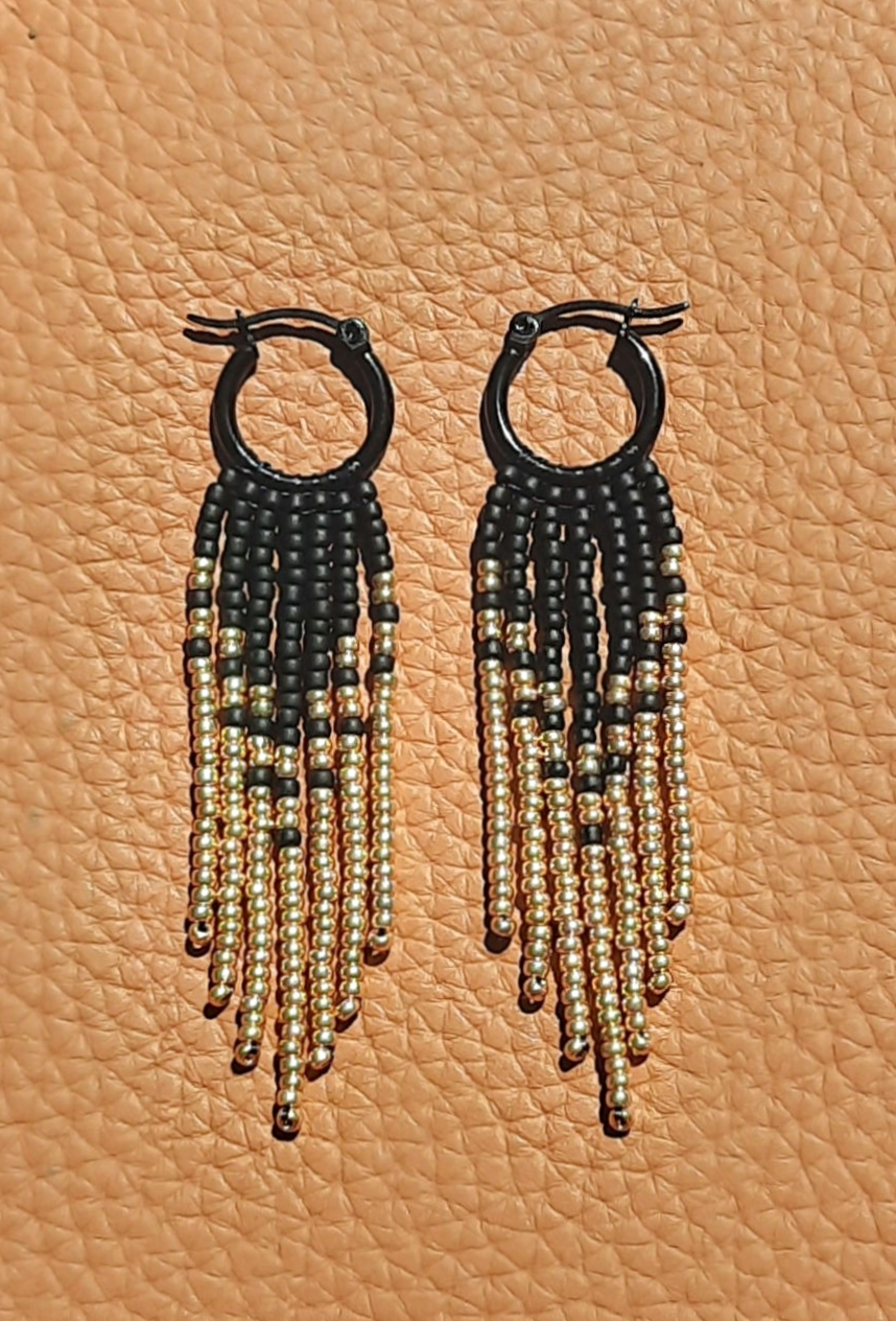 Thumbnail: Lightweight handmade black and gold seed bead fringe earrings stitched onto black stainless steel hoops with a hinged latch.