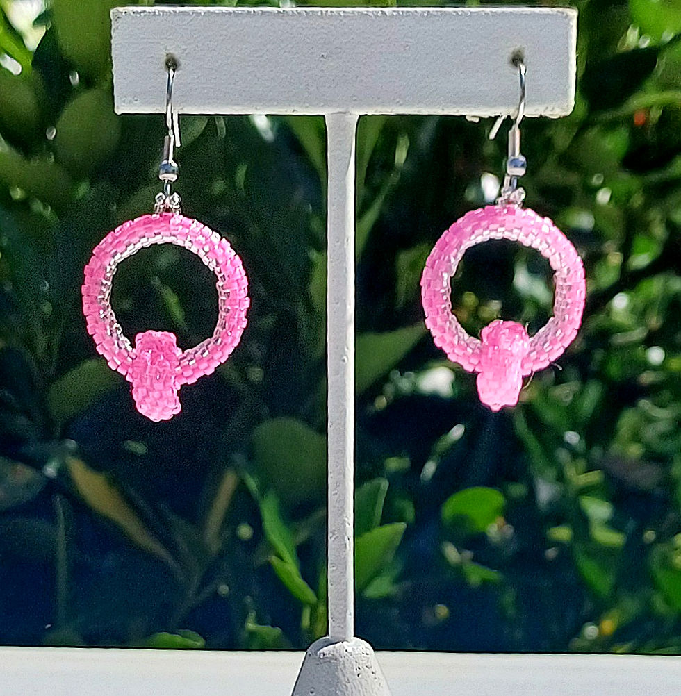 Thumbnail: pink seed bead hoop earrings with a smaller connected pink seed bead hoop on a display