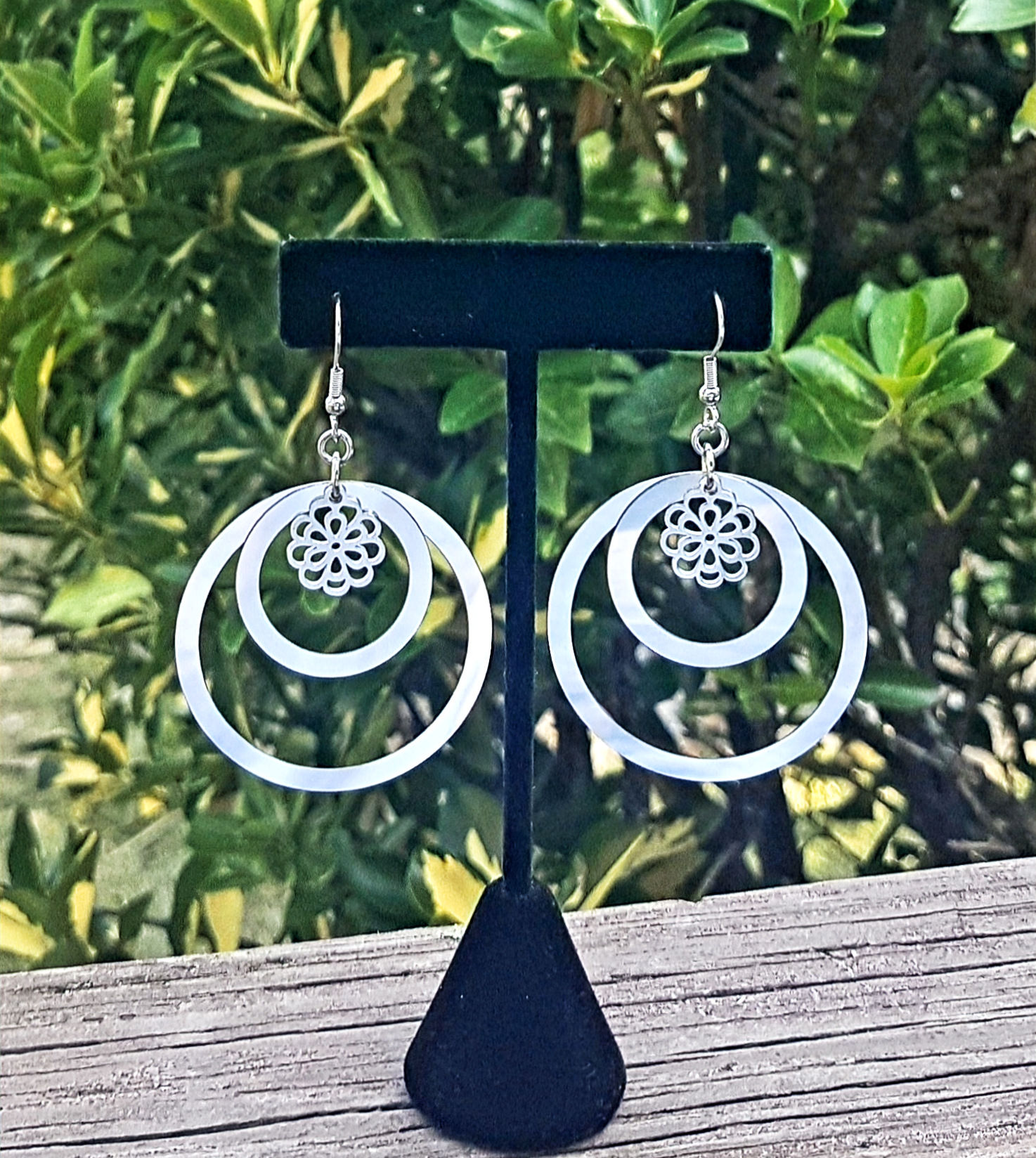 Stainless-steel hoop earrings created with laser cut circles and a stainless-steel flower charm.