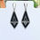 Thumbnail: Triangular silver, gray and black beaded earrings on a white display stand