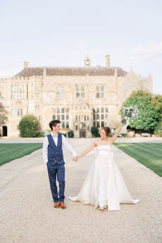 Newlyweds walking before a historic manor house.