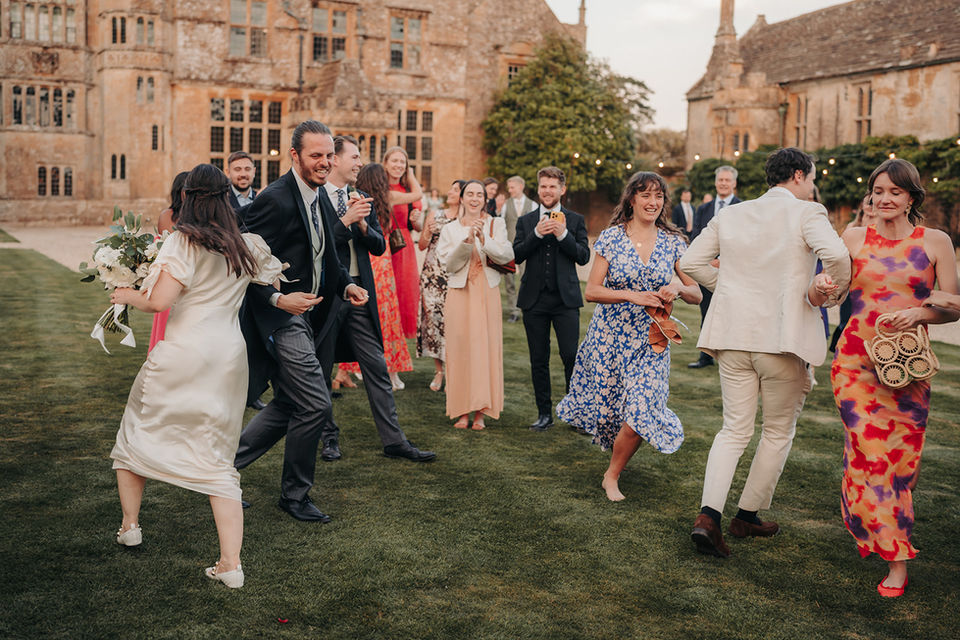 Wedding guests dancing on the lawn of a historic estate.