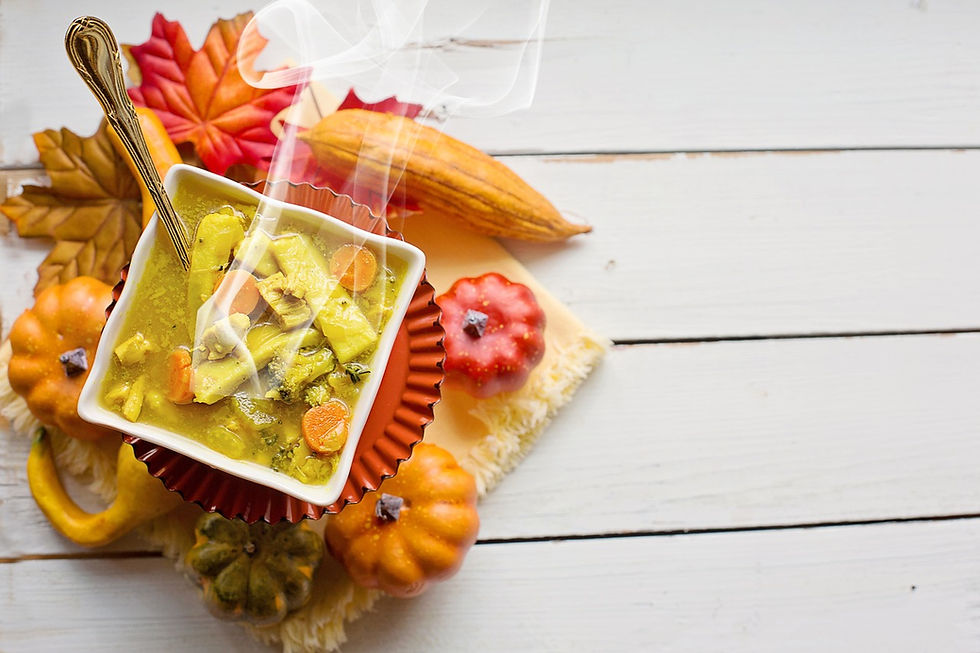 A bowl of chicken noodle soup in an square bowl and autumn table arrangement.