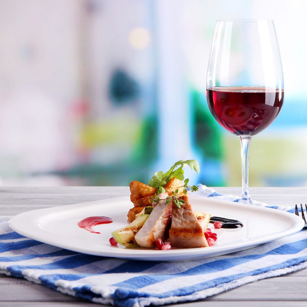 Copa de vino tinto y plato de comida bien presentada