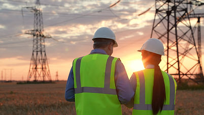 Electrician with tablet shows electric power transmission lines to inspector in sunset fie