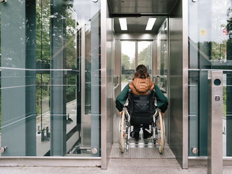Person using a wheelchair entering a modern, accessible elevator in a public building.