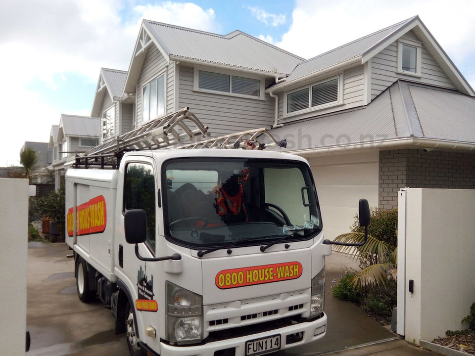 A signwritten truck with The House & Building Wash Company branding parked outside a house