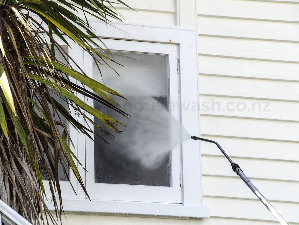 A window being sprayed with water coming out of a soft washing wand.