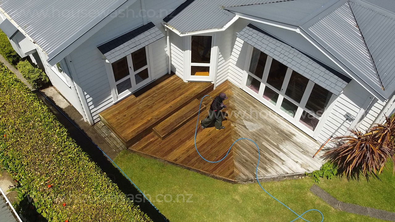 A wash tech cleaning a wooden deck