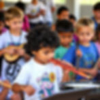 a diverse group of children playing instrument in a summer camp setting.jpg